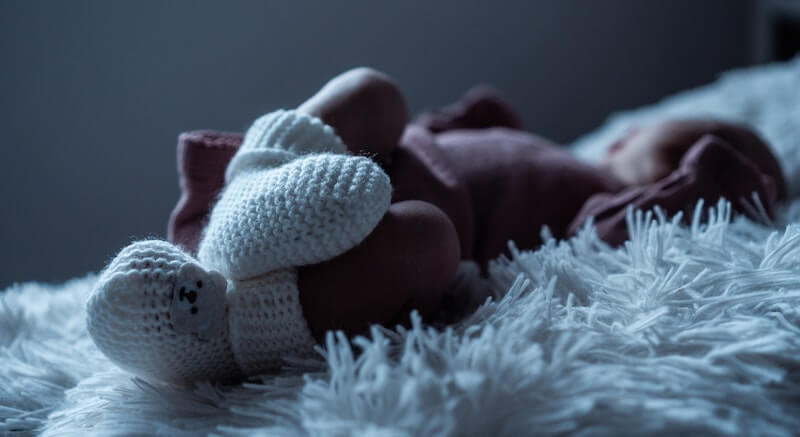 un bébé dormant avec des chaussons en laine aux pieds